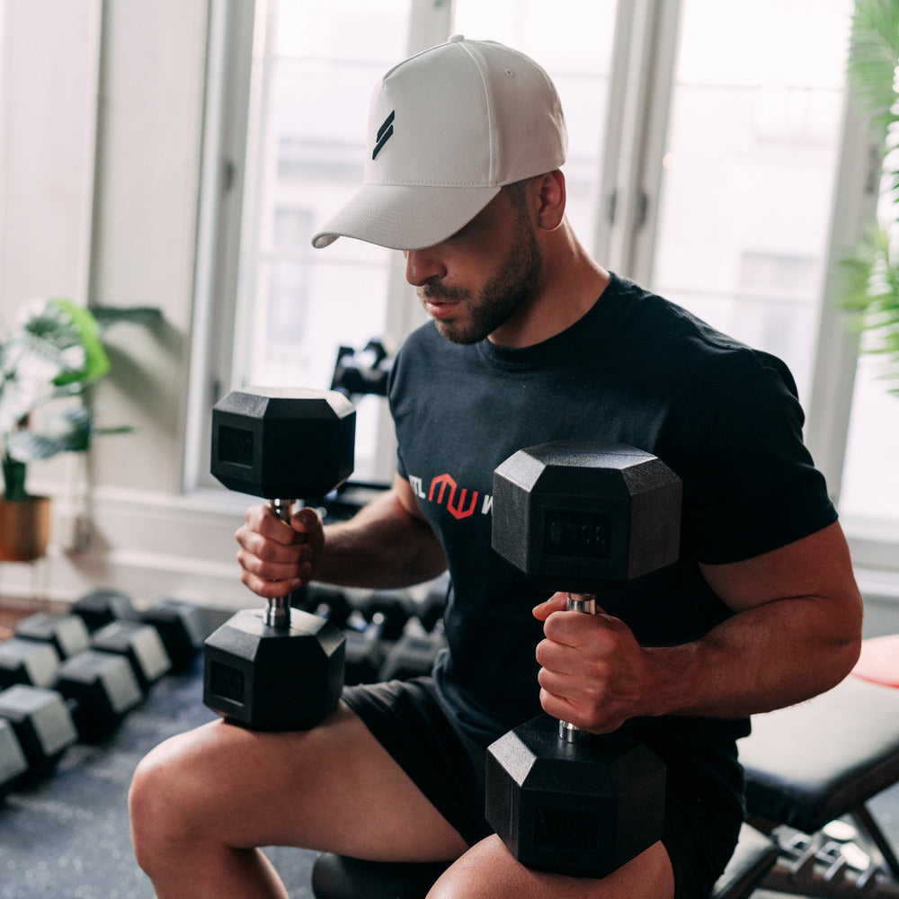 man sitting on bench holding dumbbells