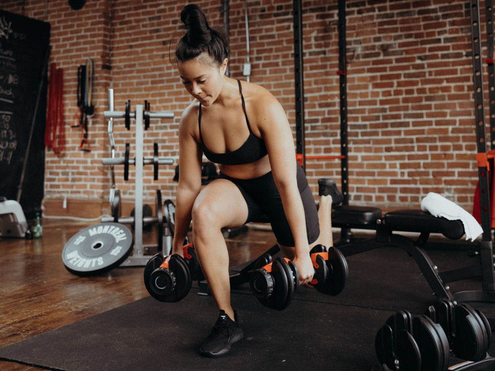 woman squatting with adjustable dumbbells