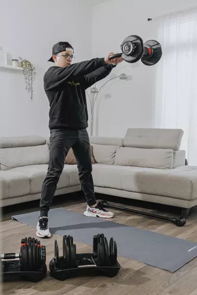 Woman in workout attire lifting a kettlebell in a living room setting.