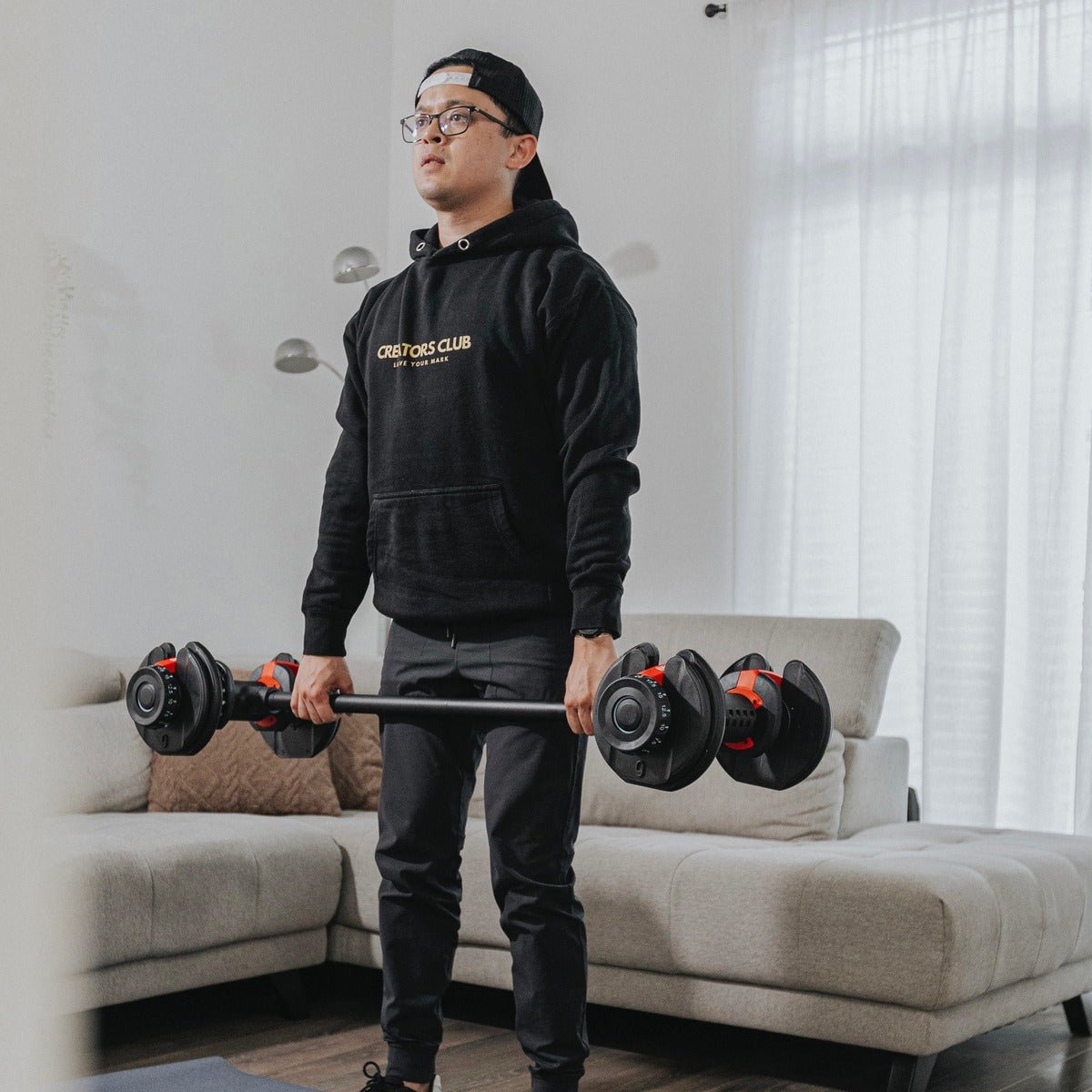 Person lifting a barbell in a living room.